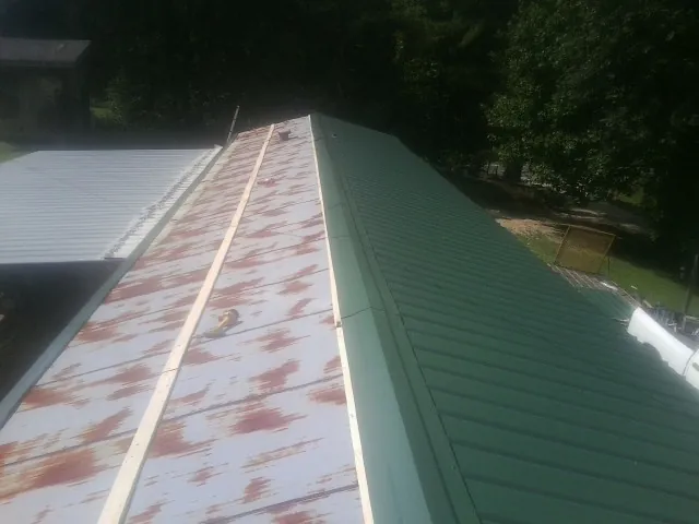 Old rusted panels beside newly installed green metal roofing — Wind Damage Roof Repair by Roofing Brothers in Pinellas Park