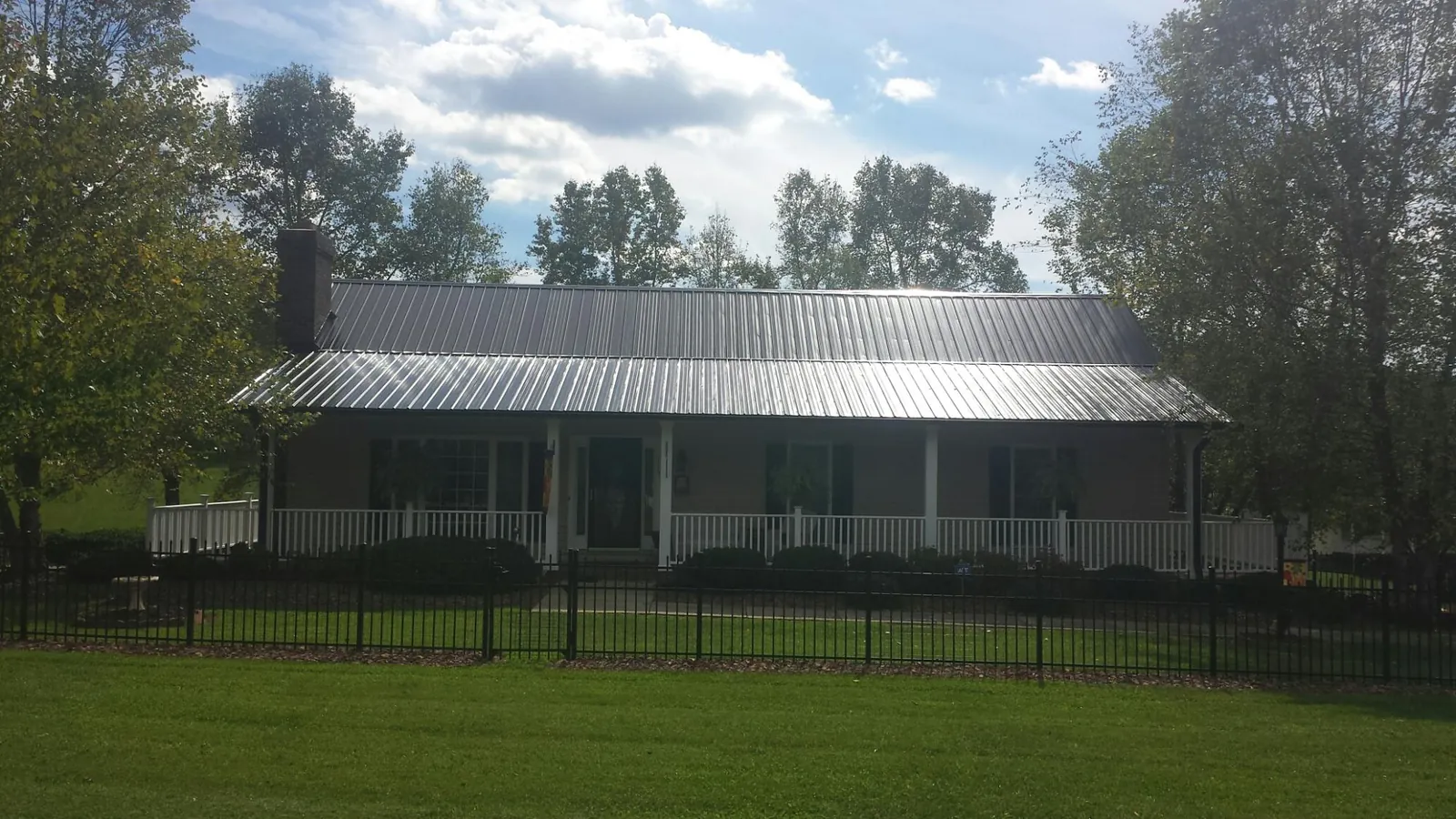 Gray metal roof on a brick ranch with a full width front porch — Gutter Guard Installation work by our crew in Pinellas Park