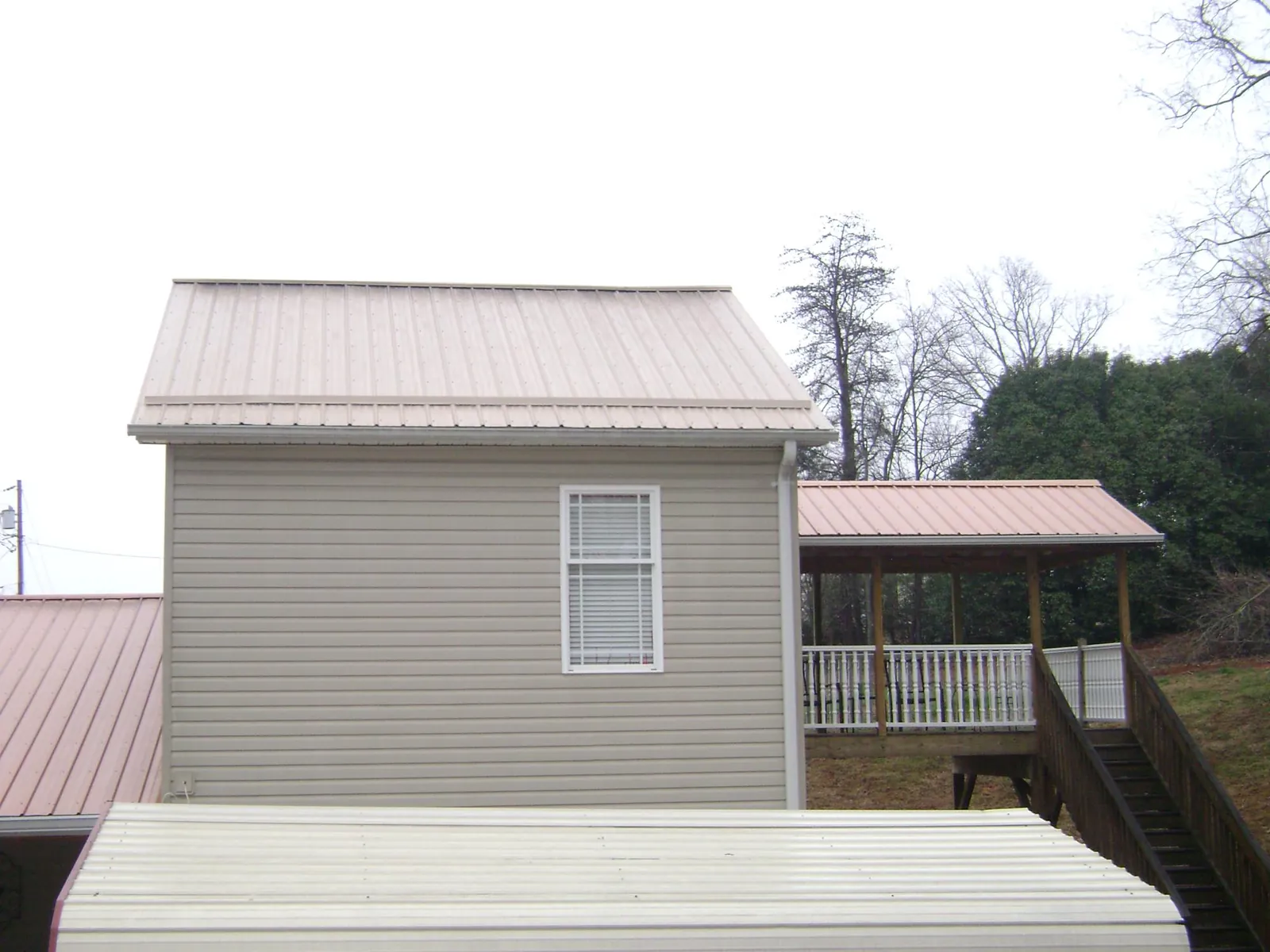 Tan metal roofs on a two story addition and attached porch, from a Roof Replacement job in Pinellas Park