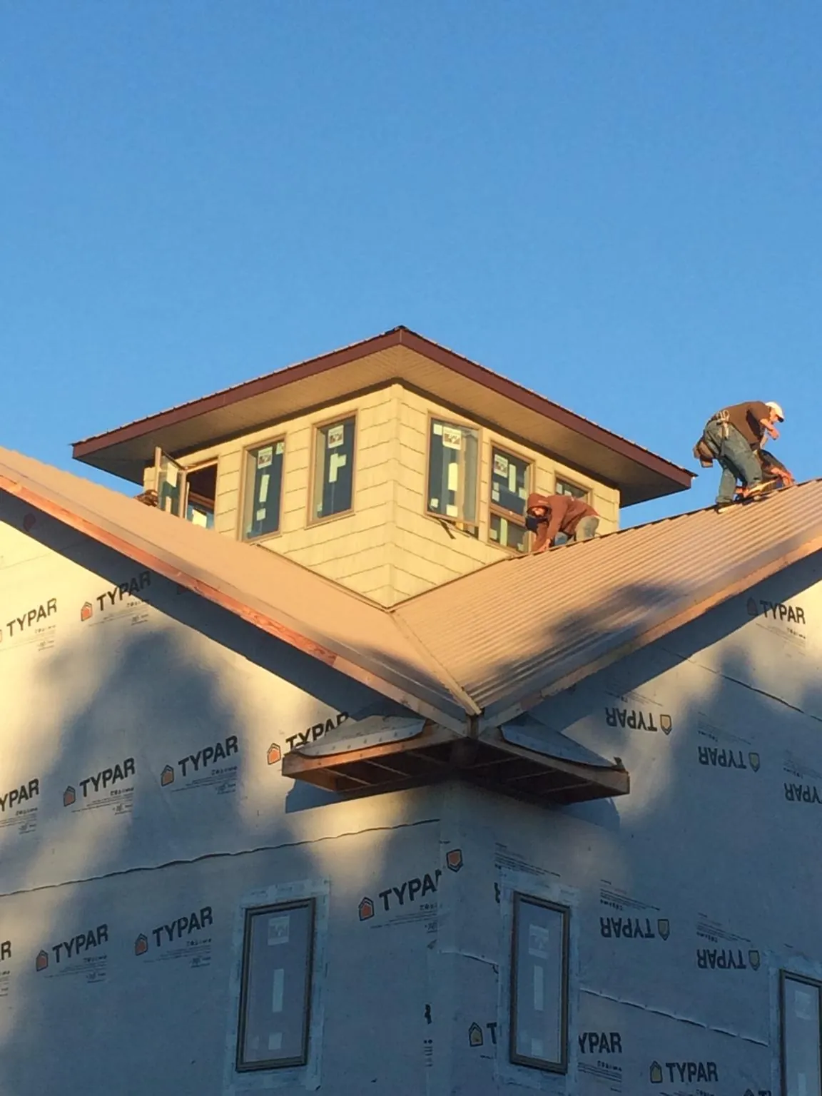 Roofers working around a rooftop cupola on a new metal roof at sunset — Roof Waterproofing in Pinellas Park by Roofing Brothers